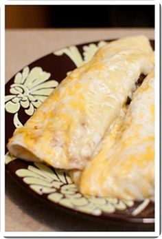 two burritos sitting on a plate with cheese