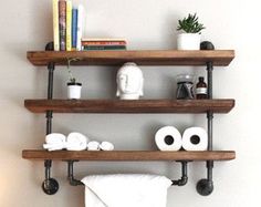 two wooden shelves holding towels, books and other items in a white room with a lamp on the side