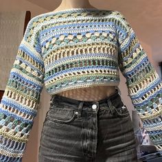 a mannequin is wearing a multicolored knitted cropped sweater and jeans