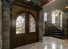 an entryway with stone walls and stairs leading up to the second floor, along with a wrought iron door