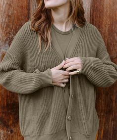 a woman standing in front of a wooden wall with her hands on her chest and looking up