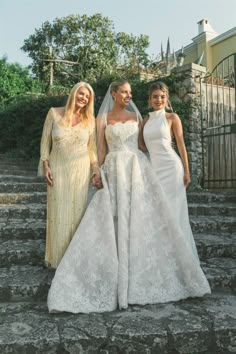 three brides standing on the steps in their wedding gowns and veils, smiling for the camera