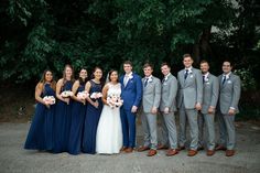 a group of people standing next to each other in front of some trees and bushes