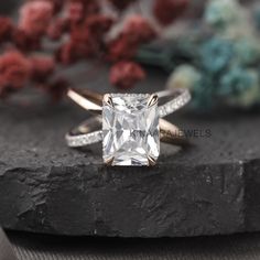 an engagement ring with a princess cut diamond in the center on top of a rock