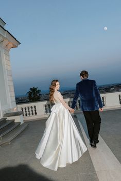 a bride and groom walking towards the moon on their wedding day in front of a building