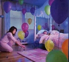 a woman kneeling down in front of a bed with balloons