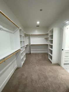 an empty walk in closet with white shelving and tan carpeted flooring is shown