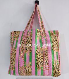 a pink and green tote bag hanging on a wall