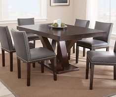 a dining room table with grey chairs and a brown rug