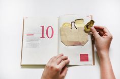 a person is holding a piece of paper in front of an open book with the number ten on it