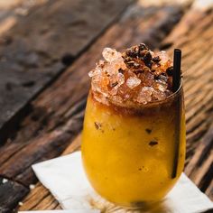 a drink sitting on top of a white napkin next to a wooden table covered in ice