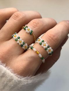 a woman's hand with three different rings on her fingers and one is wearing a white sweater