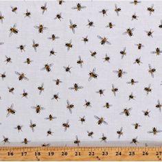 a ruler is next to a white fabric with bees on it