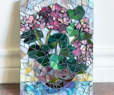 a vase filled with pink flowers sitting on top of a tile covered floor next to a wall