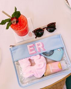 the contents of a personal care bag on a table next to a drink and sunglasses