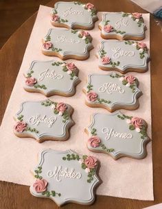 decorated cookies with name tags and flowers on the top are sitting on a pink napkin