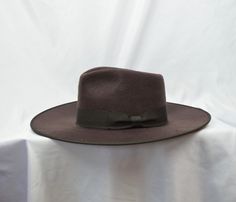 This dark brown soft high quality brushed felt flat brim 4-inch fedora with pinched fedora crown has a 1 1/2 inch grosgrain ribbon with a bow around the crown and an elastic tie in the crown which will fit up to a 57CM (22 5/8 inch) head size. Brown Brimmed Felt Hat For Formal Occasions, Brown Fedora Felt Hat For Formal Occasions, Brown Formal Fedora With Curved Brim, Formal Brown Fedora Felt Hat, Formal Brown Fedora With Curved Brim, Formal Western Boater Hat With Wide Brim, Brown Wide Brim Fedora For Formal Occasions, Brown Formal Fedora Hat, Formal Brown Fedora Hat