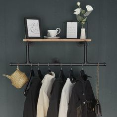 clothes hanging on a rack in front of a gray wall with white flowers and pictures