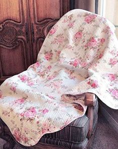 a chair with a blanket on top of it in front of a wooden armoire