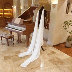 a wedding dress hanging on a mannequin in front of a grand piano