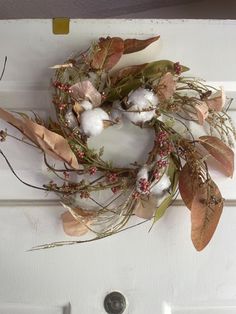 a wreath hanging on the front door with cotton balls and dried leaves in fall colors