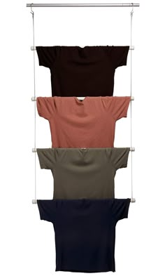 four t - shirts hanging on a clothes rack with three different colors and sizes in them