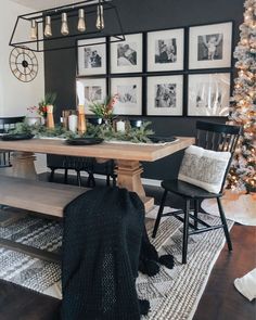 a dining room table with chairs and pictures on the wall behind it, surrounded by christmas decorations