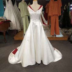 a white wedding dress on display in a room with mannequins and other dresses