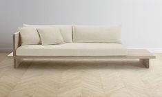 a white couch sitting on top of a hard wood floor next to a wooden table