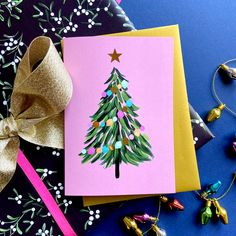 a card with a christmas tree on it next to other holiday decorations and gifts around it