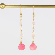 These elegant hand-wired earrings showcase a classic drop design adorned with two pink Jade gemstones, four pale pink Morganite stones, and two luxurious South Sea Pearls. With a 3.25" drop and crafted from gold-plated metal, they add a refined touch to any look. Pink Jade is believed to promote love, reduce stress, and bring luck, while pink Morganite is believed to foster joy and emotional calm. South Sea Pearls are thought to enhance clarity, aid self-expression, and boost self-esteem, making Pink Pearl Drop Teardrop Earrings, Pink Teardrop Pearl Drop Earrings, Pink Feminine Dangle Pearl Earrings, Pink Long Drop Earrings As Gift, Elegant Pink Long Drop Earrings, Pink Pearl Drop Dangle Earrings, Pink Dangle Pearl Earrings With Ear Wire, Pink Teardrop Pearl Drop Jewelry, Pink Dangle Pearl Earrings