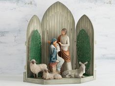 a nativity scene with figurines of people and animals in front of a wooden fence