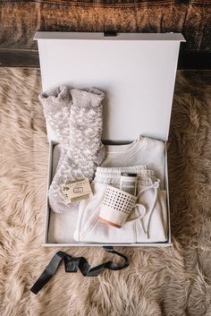 an open white box with items inside on a fur rug next to a black ribbon