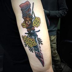 a person with a knife and flowers on their arm