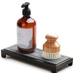 a soap dispenser sitting on top of a shelf next to a brush