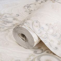 a roll of white fabric sitting on top of a bed next to a wallpaper