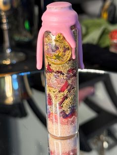 a pink and gold colored glass bottle with liquid pouring out of it's top