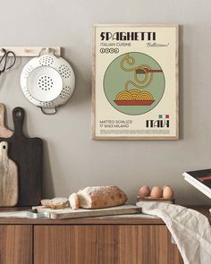 a poster hangs on the wall above a counter with bread and other kitchen utensils