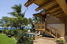 a house with an ocean view and lush green lawn area next to the swimming pool