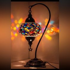 a stained glass lamp on a stand in front of a wall with multicolored lights