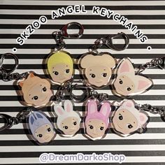 six keychains with cartoon faces on them sitting on a black and white striped surface