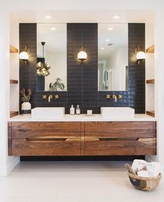 a bathroom with two sinks, mirrors and lights on the wall in front of it