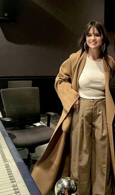 a woman standing in front of a computer desk with a keyboard and monitor behind her