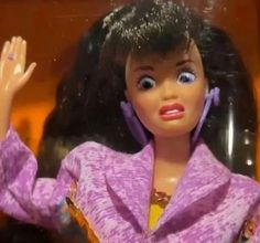 a close up of a barbie doll wearing a purple jacket and holding her hand in the air