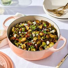 a pink pot filled with brussel sprouts and other food on top of a table