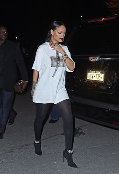 a woman in tights and heels walking down the street at night with her hand on her hip