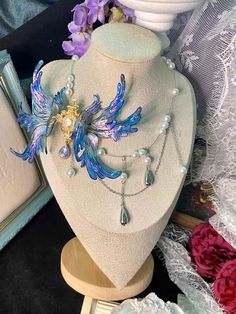 Dive into a world of enchantment with our Ethereal Mermaid Fairy Wing Choker. This stunning piece embodies the magic where sea meets sky, blending the allure of mermaids with the whimsy of fairies. Key Features: * Handcrafted iridescent wings that shimmer with every movement * Mesmerizing blue and purple hues reminiscent of twilight over calm seas * Unique asymmetrical design featuring a delicate gold-toned centerpiece * Choker style for a close, elegant fit Artisan Craftsmanship: Each wing is a Ethereal Mermaid, Ethereal Fairy, Iridescent Wings, Fantasy Necklace, Ren Fair, Magical Accessories, Mermaid Fairy, Iridescent Blue, Wing Necklace