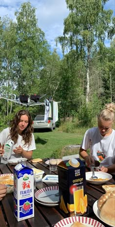 three people sitting at a picnic table with food