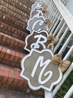 three wooden signs with bows on them are sitting on the side of a set of stairs