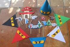 a table topped with cake toppers next to party hats and legos on sticks